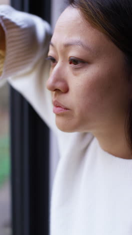 Vertical-Video-Close-Up-Of-Stressed-Or-Anxious-Woman-Suffering-With-Depression-Anxiety-Loneliness-Or-Agoraphobia-Leaning-Against-Window-At-Home-4